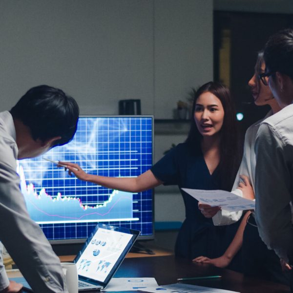 Asia businessmen and businesswomen meeting brainstorming ideas conducting business presentation project colleagues working together plan success strategy enjoy teamwork in small modern night office.